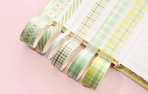 Close-up of green and yellow plaid washi tape rolls used on notebook pages