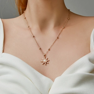 Close-up of rose gold sun pendant necklace with opal stone worn on model's neck