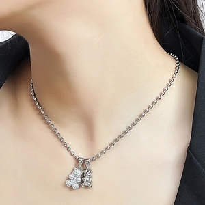 Detail of silver ball chain necklace featuring a crystal-encrusted bear and a polished bear