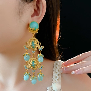 Detail of vintage flower hollow earrings with green gemstones worn by a model