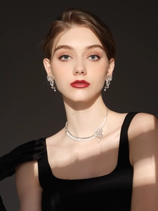 Close-up of model wearing luxury crystal flower earrings and a matching pearl necklace
