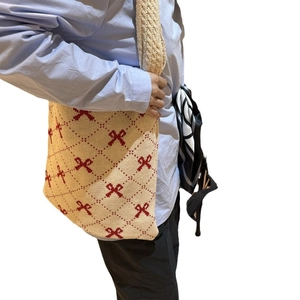 Chic beige knitted tote bag with red bow pattern and diamond lattice on a model