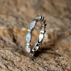Detailed macro view of white gold band with oval opals and sparkling diamonds