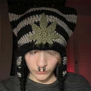 Detail of hand-knitted striped beanie with green leaf embroidery and tassels