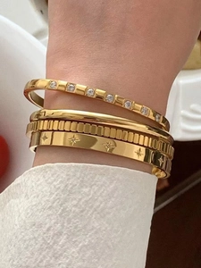 Detail of four-piece gold plated bangle set with zircon and starburst engraving
