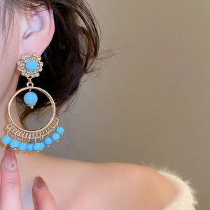 Macro detail of bohemian gold earrings with blue turquoise beads and sparkling rhinestones