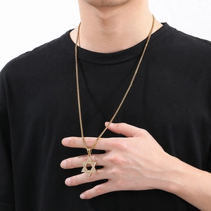 Detail of gold iced out hexagram star pendant with box chain on male model wearing black tee