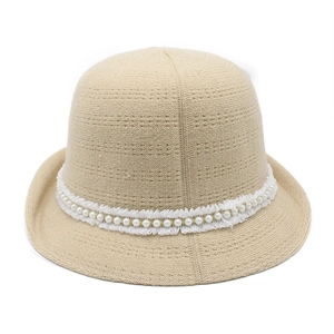 Close-up of pearl beads and white lace trim on a beige knit bucket hat detail
