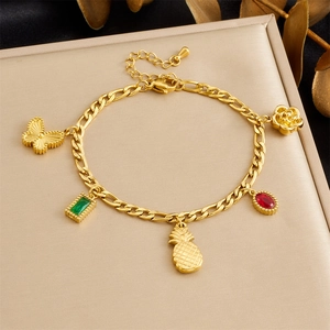 Detail van vergulde armband met vlinder, ananas en edelsteen bedeltjes voor dames