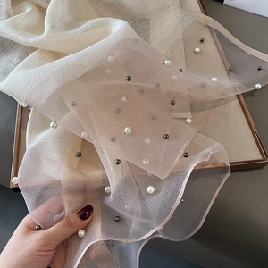 Detail of champagne silk scarf with pearl beads showing light mesh texture and drape