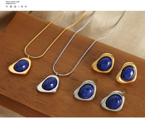 Macro shot of geometric gold necklace with inlaid blue lapis stone on silk background