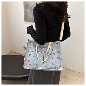 Light blue shoulder bag with cherry print featuring woven handles and detachable strap
