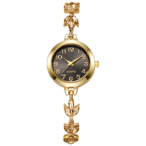 Macro detail of gold watch band featuring clover-shaped rhinestones and grey dial face