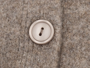 Macro detail of round matte button on beige mohair knit cardigan with fuzzy texture
