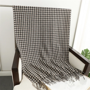Detail of classic plaid pattern and long tassels on soft knit scarf over a white chair