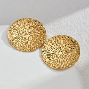 Détail macro de boucles d'oreilles rondes dorées avec une texture martelée ondulée unique