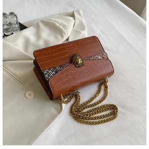 Close-up of brown crocodile texture handbag with vintage gold lion head buckle and chain