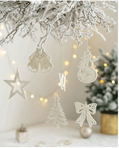 Close-up of glittery silver Christmas tree ornaments hanging on snowy pine branches