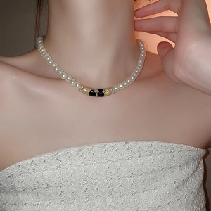 Gros plan détaillé du collier de perles vintage avec pendentif strass noir et or sur le cou
