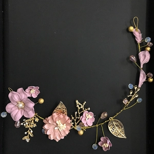Detail of handmade bridal headpiece with purple fabric flowers and golden metal leaves