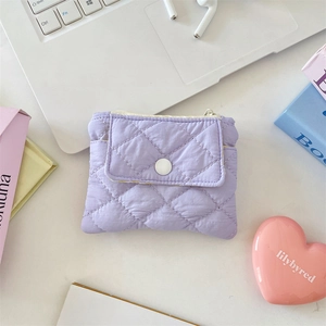Purple quilted diamond pattern wallet with snap pocket and zipper on a desk