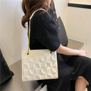 Close-up of beige crossbody bag featuring 3D geometric texture and gold chain strap