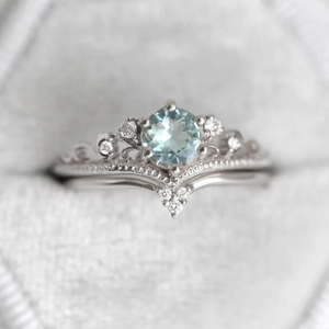 Macro shot of silver princess crown ring set with a blue round gemstone in a jewelry box