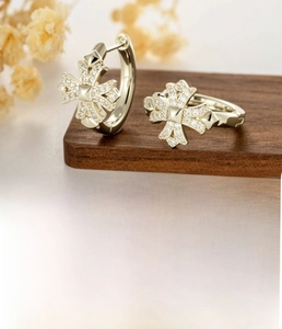 Detail of light coffee gold cross hoop earrings with copper and zircon material specs