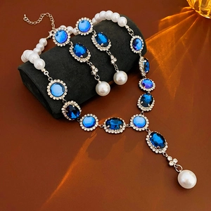 Dettaglio della collana con gemme blu, perle ovali e alone di cristalli scintillanti