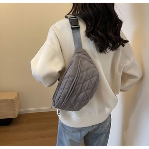 Rear view of a grey quilted crossbody bag featuring a wide adjustable strap and buckle