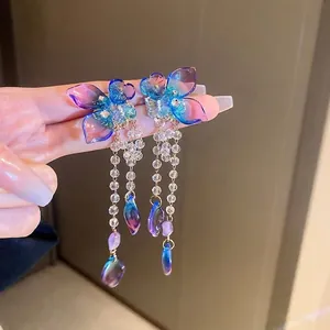 Detail of butterfly drop earrings with iridescent gradient wings and crystal tassels