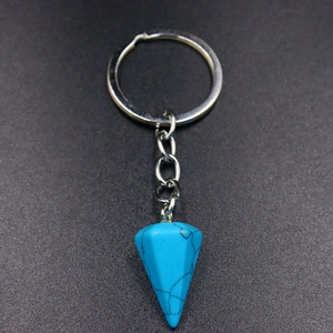 Natural turquoise hexagonal stone cone keychain with silver metal ring on black background