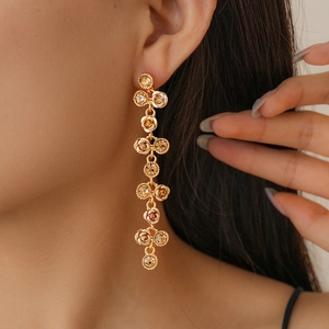 Détail de longues boucles d'oreilles dorées à pompons et fleurs en cristal sur le mannequin