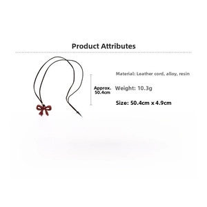 Macro detail of red resin bow pendant on black cord necklace showing materials