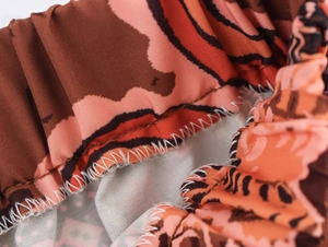 Detail view of abstract orange leopard print fabric with elastic waistband and stitching