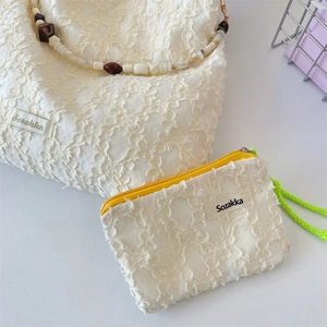 Detail of floral lace texture on white shoulder bag set with colorful beaded handle