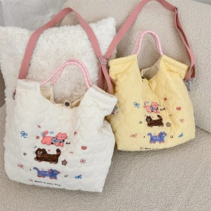 Detail of cartoon cat embroidery and heart quilting on quilted crossbody bag with plaid handles