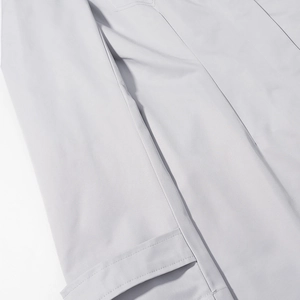Detailed close-up of side pocket and precise double stitching on light gray blazer