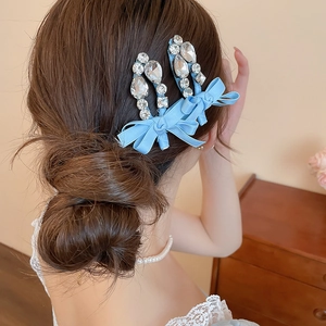 Détail d'une pince à cheveux avec nœud en soie bleue et cristaux en forme de goutte d'eau