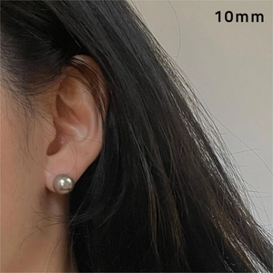 Close-up of 10mm dark grey pearl stud earrings worn by a model for size perspective