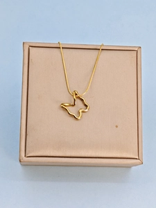 Detail of a gold butterfly pendant necklace resting on a beige jewelry gift box