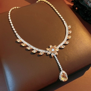 Detailed close-up of golden flower necklace with sparkling zircon and amber teardrop pendant