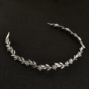 Détail d'un serre-tête argenté avec perles et cristaux sur un fond noir texturé