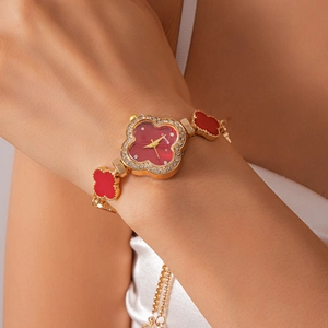 Close-up of a vintage clover flower watch with red dial and pavé stones on a female wrist