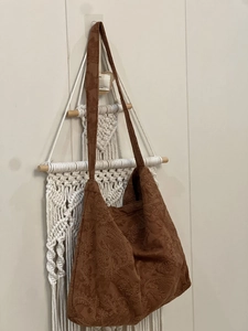 Detailed embroidery on a brown suede shoulder bag featuring bohemian floral patterns