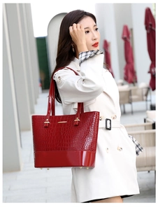 Close-up of red crocodile embossed tote bag with glossy finish and gold metal accents