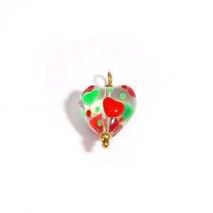 Detailed close-up of heart-shaped glass bead with red and green patterns and gold accents