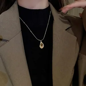 Vintage gold necklace with tiger eye stone pendant on model wearing a brown blazer