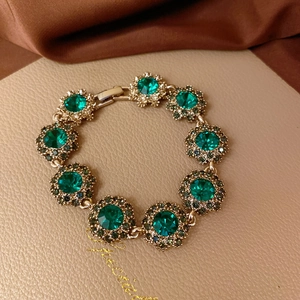 Elegant gold flower bracelet with emerald green crystals and vintage micro-pave details