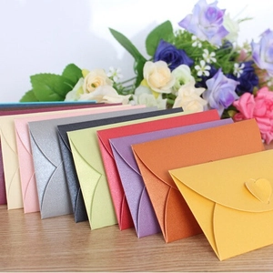 Colorful pearlescent mini envelopes with heart closure on wood table with roses